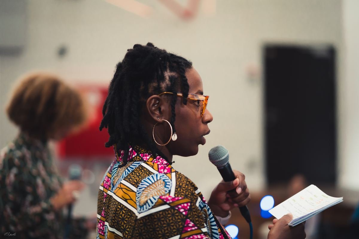 Massinda Zinga speaking into a microphone at a talk