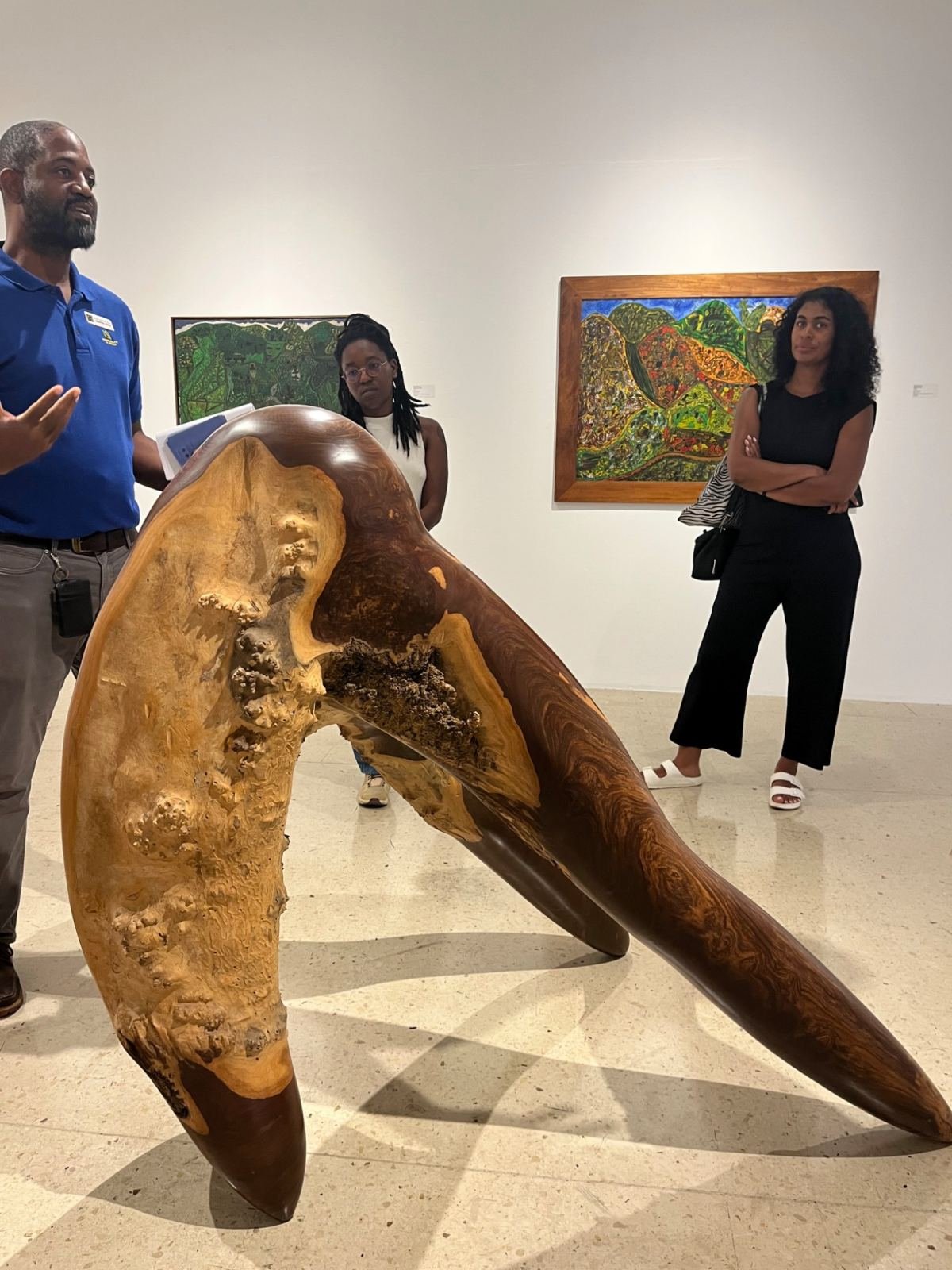 A guided gallery visit around a large carved wooden sculpture
