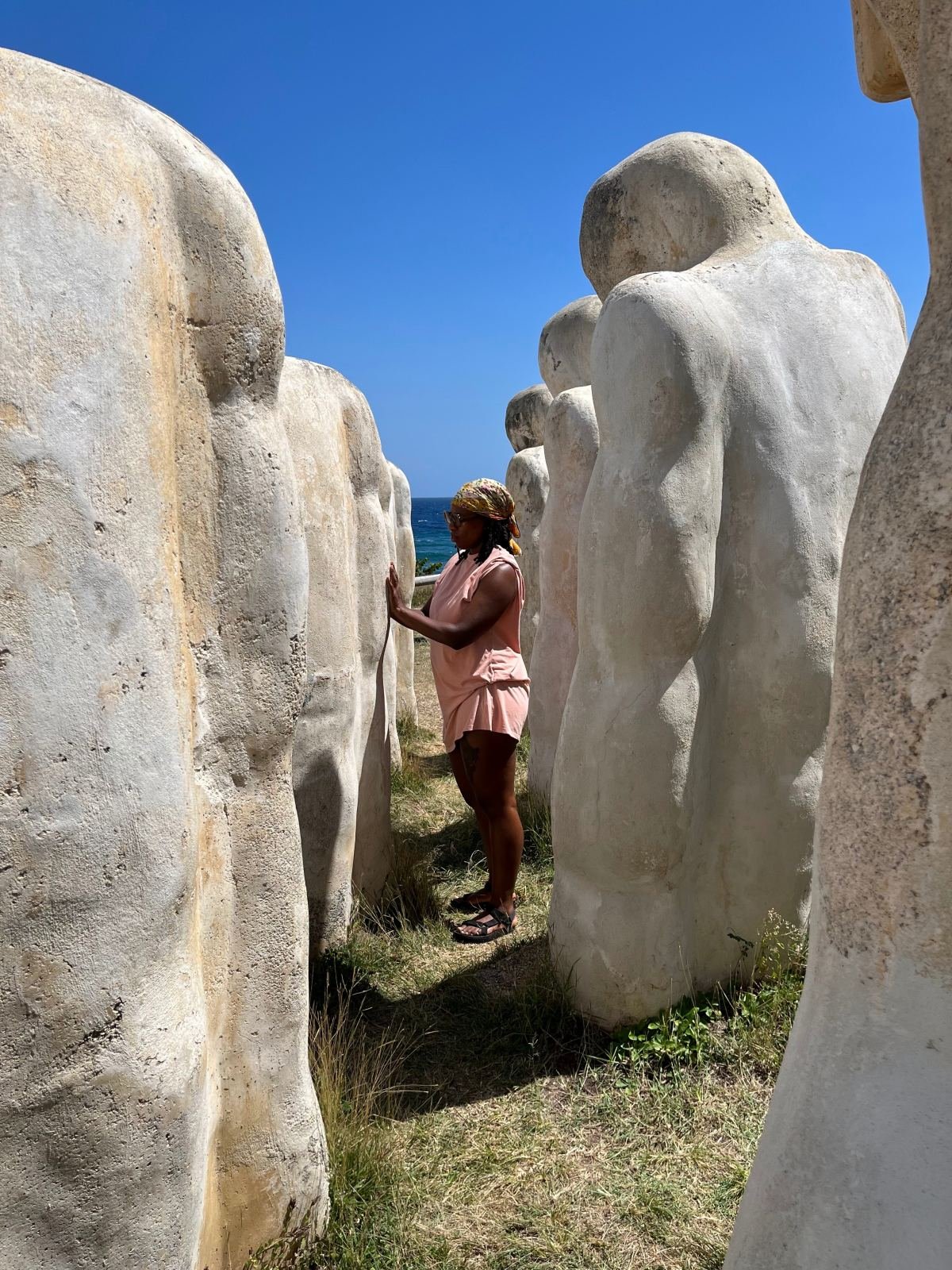 Massinda Zinga among tall white stone statues by the sea