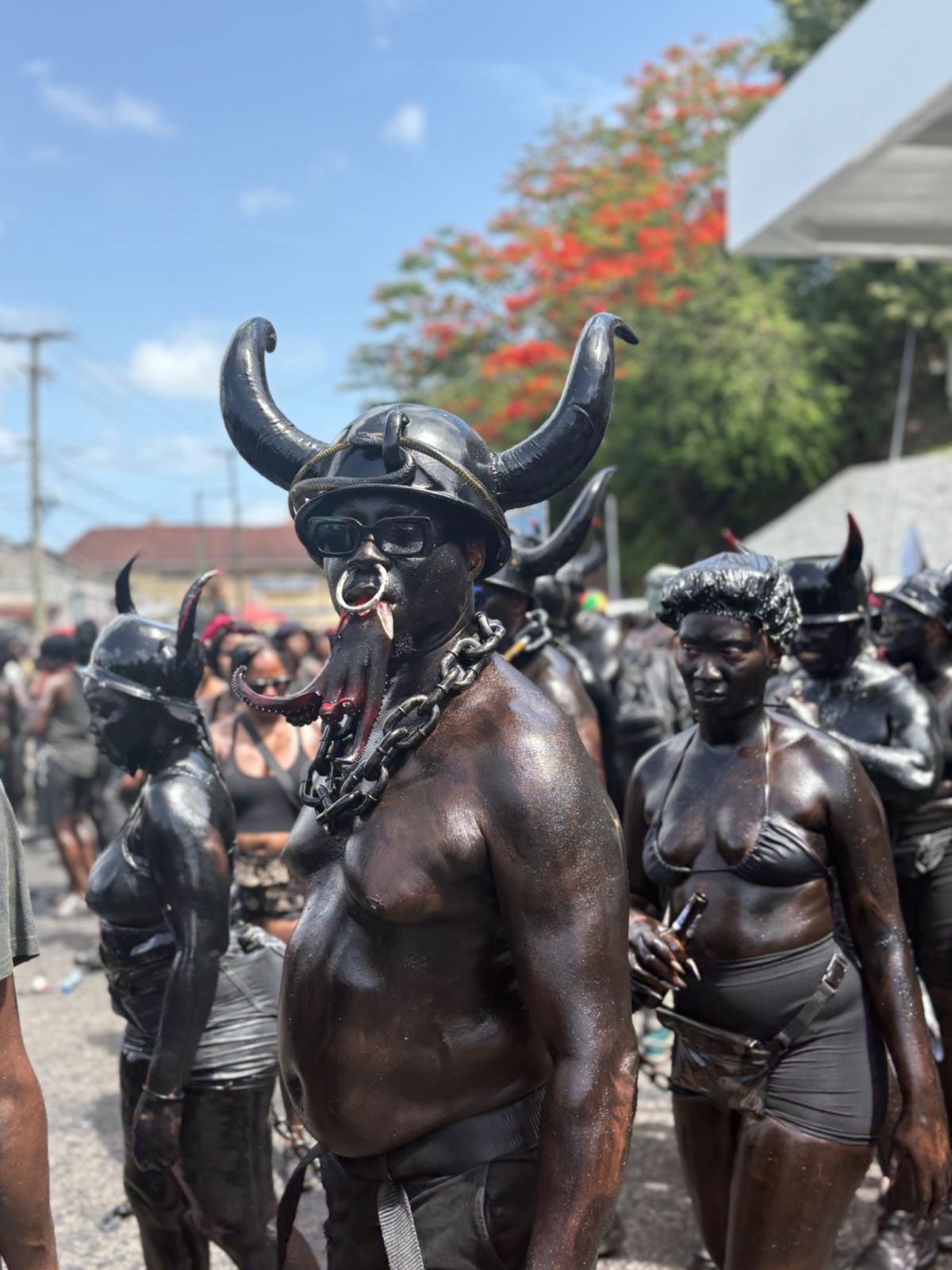 Jab Jab masqueraders covered in black, with horned helmets and chains, at carnival