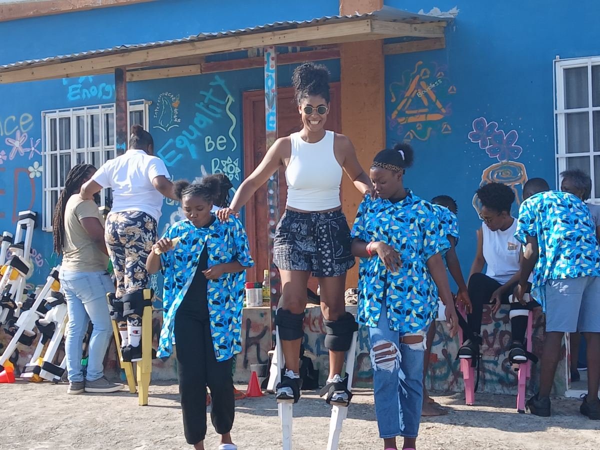 Dancers on stilts performing outside a brightly painted blue building