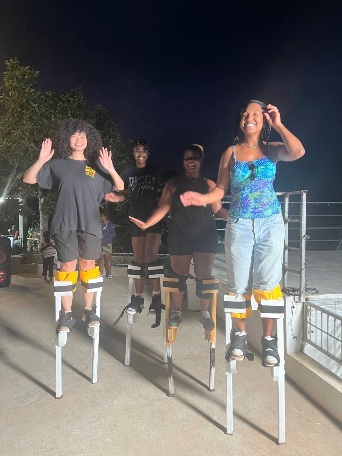 Women practising on stilts on a terrace at night