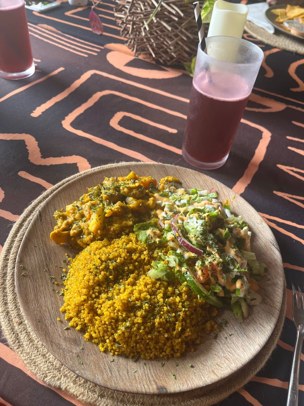 A plate of turmeric rice and salad on a patterned tablecloth