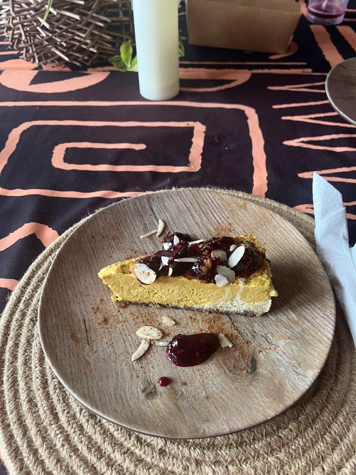 A slice of cake with jam and almonds on a wooden plate