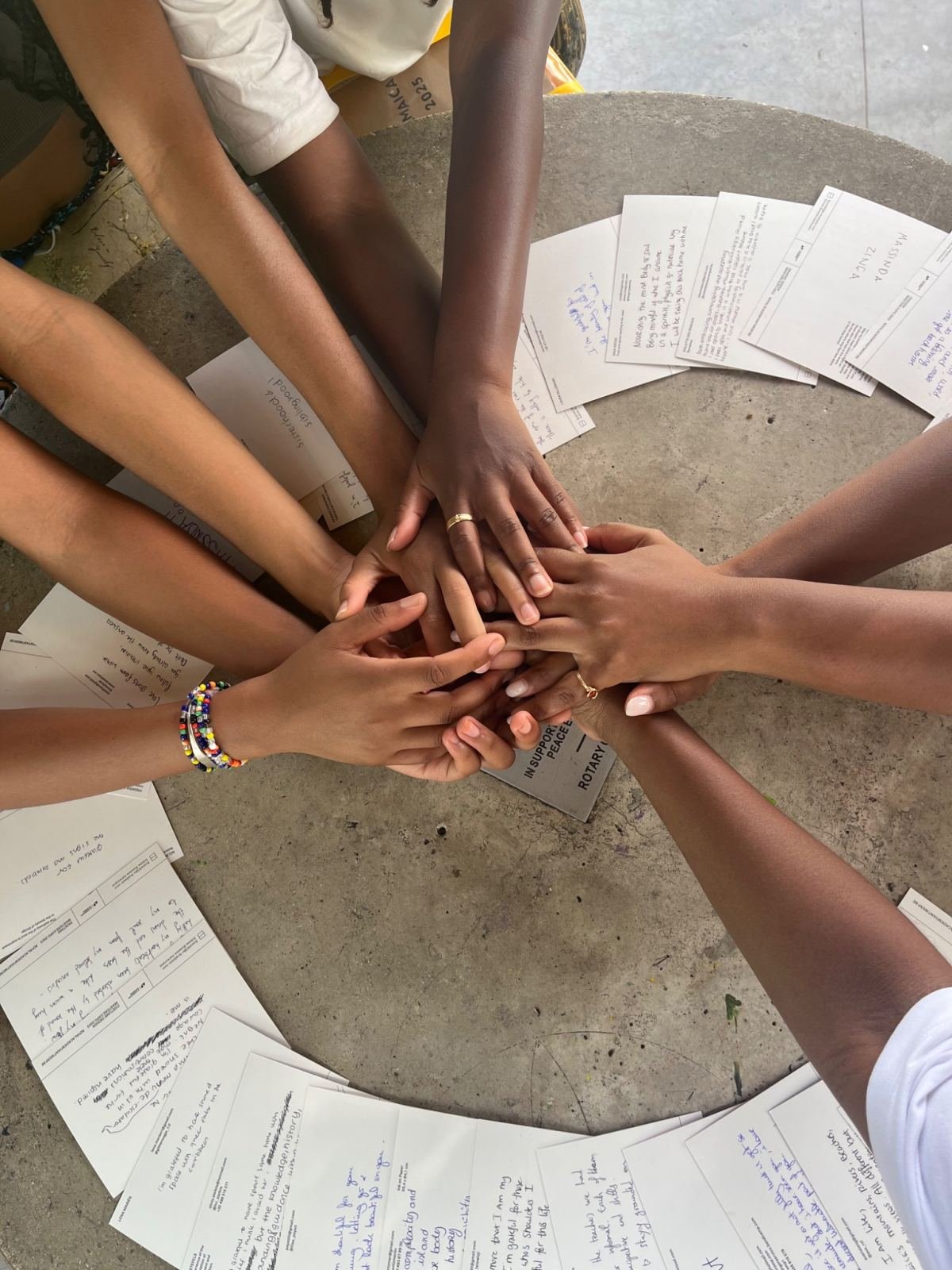 Hands stacked together in a circle over handwritten notes