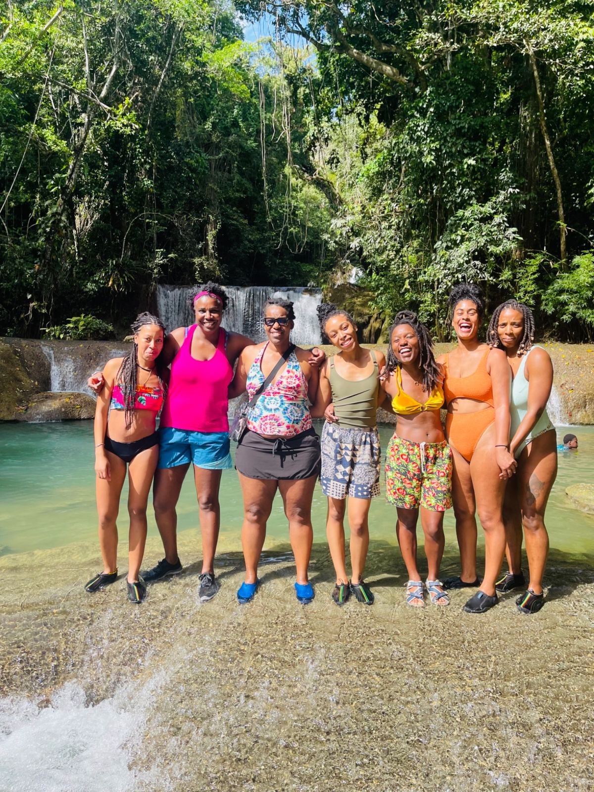 A group of women in swimwear in front of a waterfall