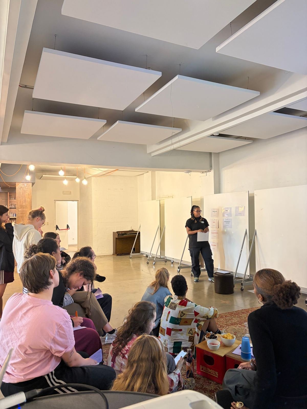 Massinda Zinga teaching a class, standing before her seated students in a studio